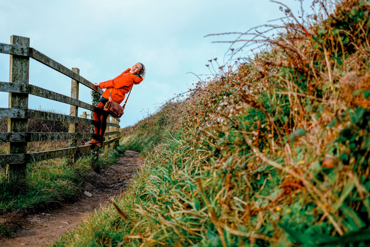Stacey climbing across a fence to avoid the muddy path.