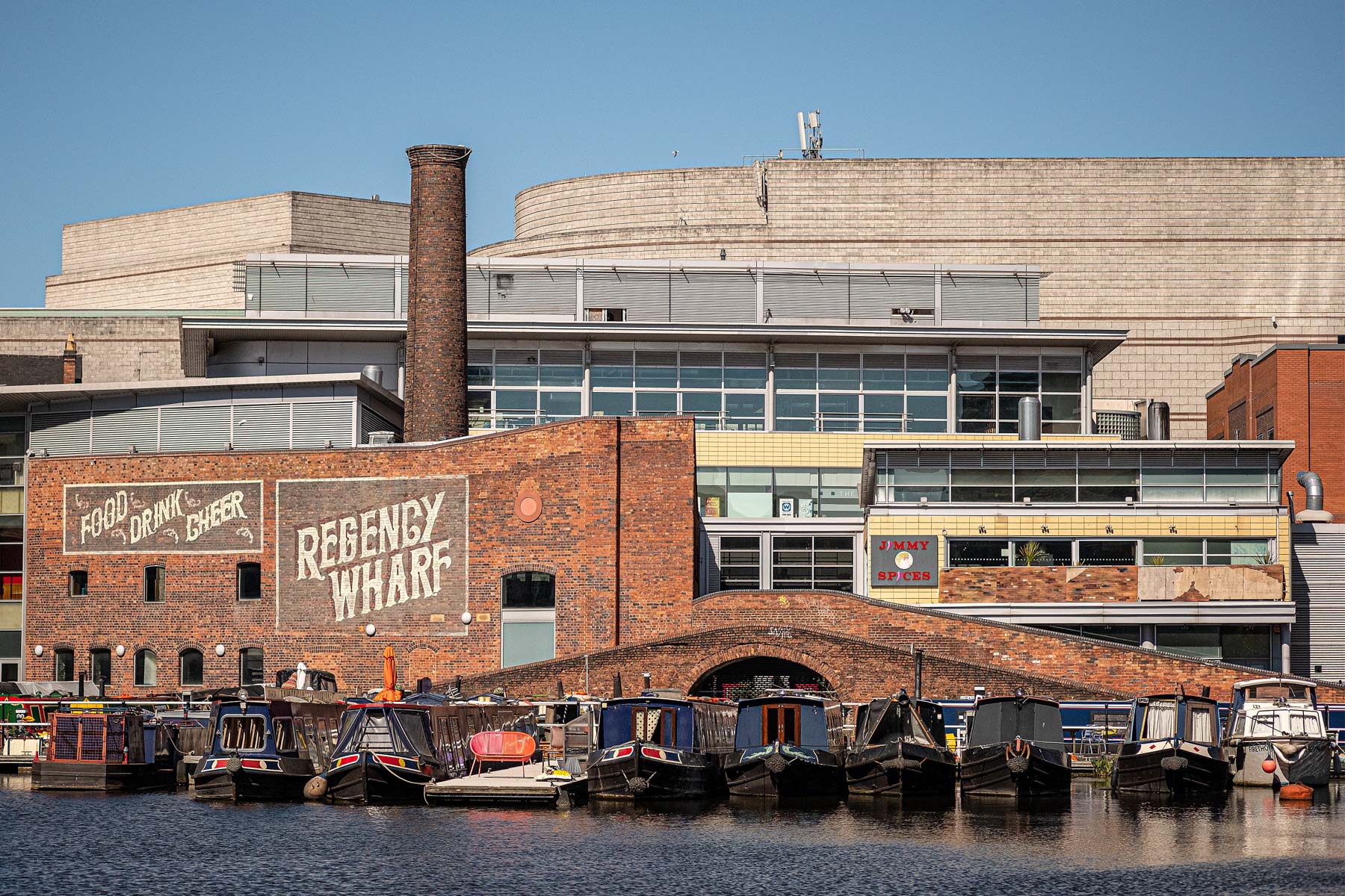 Canal boats in Gas Street Basi with buildings behind and 'Regency Wharf' written on a brick wall. Things to do in Birmingham.